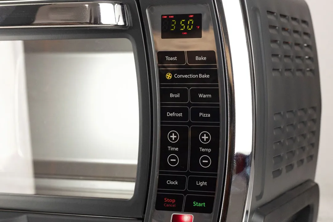 The control panel of the Oster TSSTTVMNDG-SHP-2 Toaster Oven is positioned vertically on the right side of the oven’s front. It includes an LCD and 15 buttons. On the oven’s sides are air ventilation holes.