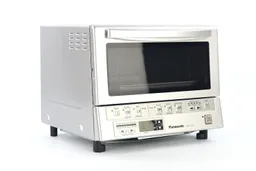 The front of a closed silver Panasonic NB-G110P FlashXpress Compact Toaster Oven has a control panel and the left has holes.