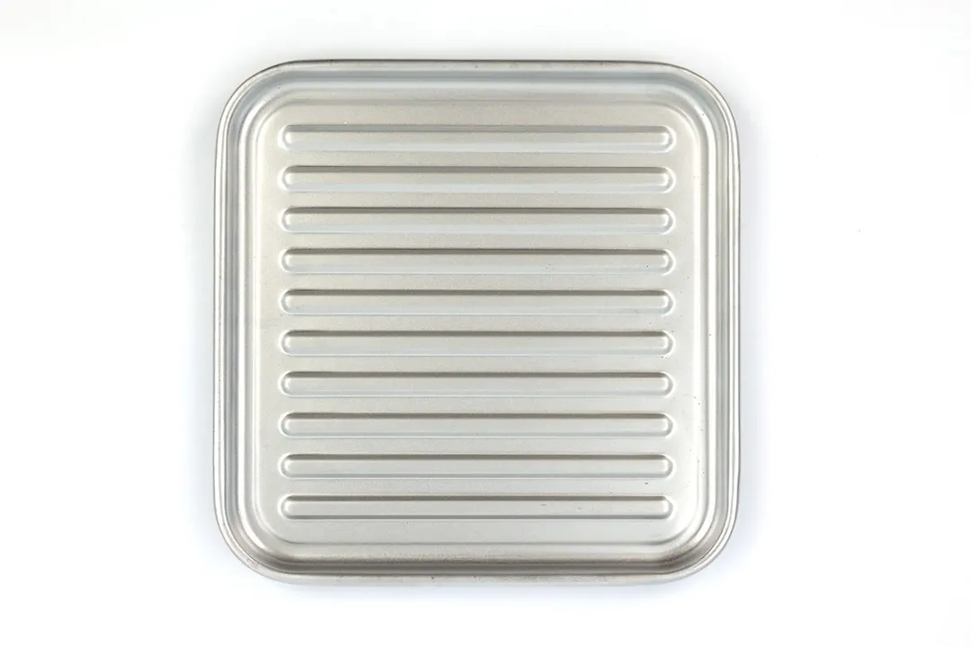 A grooved silver baking pan of the stainless steel Panasonic NB-G110P FlashXpress Compact Toaster Oven on a white background.