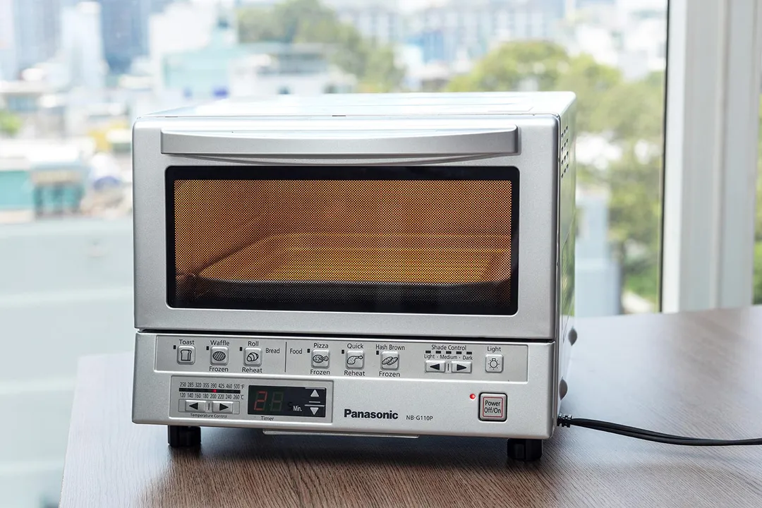 The front of a closed silver stainless steel Panasonic NB-G110P FlashXpress Compact Toaster Oven on a white background.