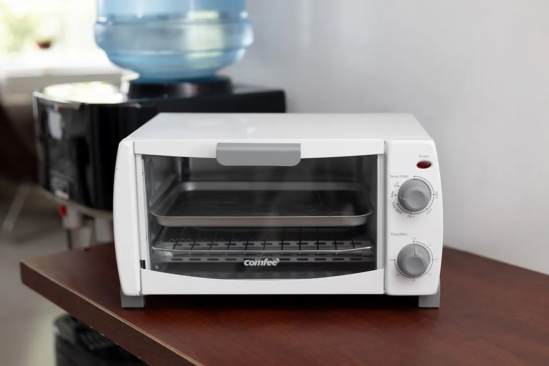 The front of a closed white COMFEE CFO-BB101 Compact Countertop Toaster Oven on a white background.