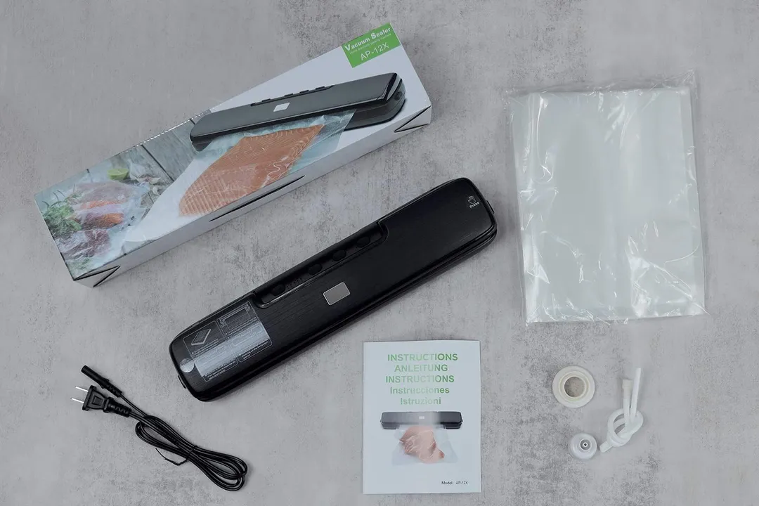 The content of the CALOTO AP-12X vacuum sealer’s shipping box. It includes a detachable power cord, air hose and adapter, sheets of pre-cut plastic bags, and an instruction manual.