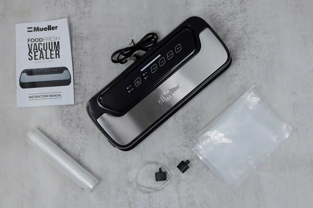 The content of the Mueller MV-1100 vacuum sealer’s shipping box. There’s the sealer itself, sheets and rolls of plastic, air hose and adapter, along with the documentation for the sealer.