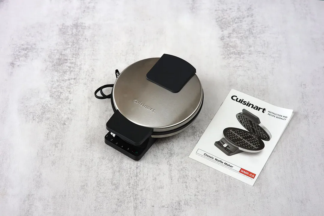 The Cuisinart WMR-CA, with its stainless steel top and black plastic detailing, sitting next to its instructional manual.