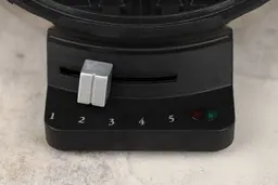 The control panel of the Cuisinart round classic waffle maker. There’s the silver browning control knob and indicator lights.