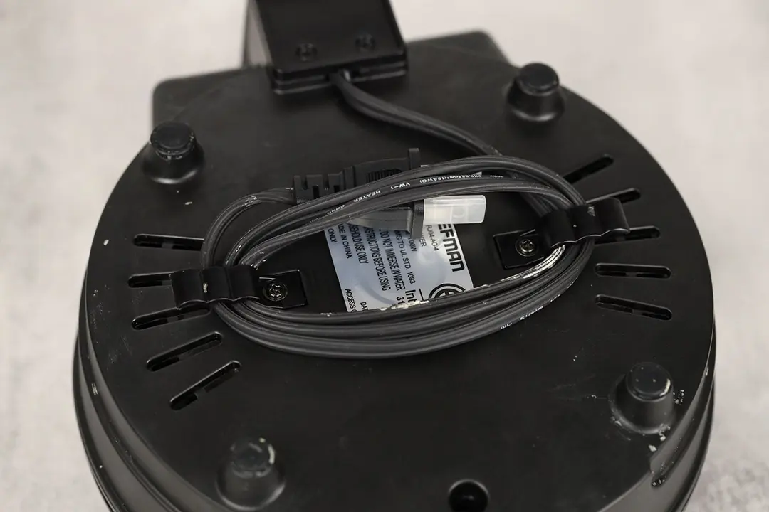 A cord grommet at the bottom of the Chefman waffle maker. It helps the user manage the cord before putting it into storage.