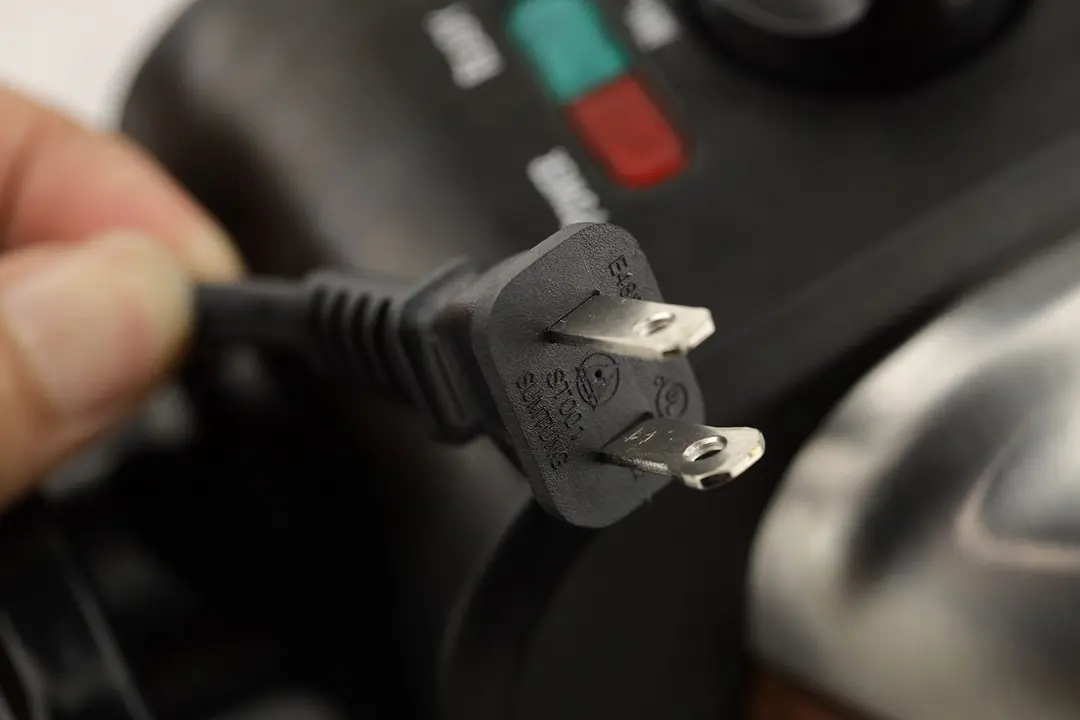 A close-up of the power cord of the Hamilton Beach 26031 waffle maker, focused on the prongs of the plug.