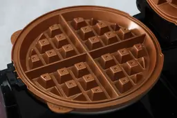 A close-up of the bronze-color, Belgian-style waffle plate of the Hamilton Beach flip Belgian waffle maker 26031.