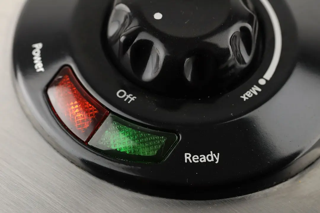 The indicator lights of the Oster waffle maker. To the left is the red POWER light, and the right is the green READY light.
