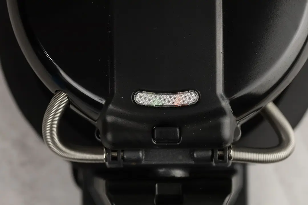 A close-up of the indicator lights on the Black and Decker WMD200B double Belgian waffle maker. Both lights are shining dimly, one green and one red.