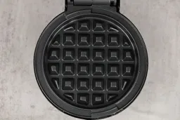 A close-up shot of the DASH Mini waffle maker’s waffle plate. It is black and treated with a layer of textured non-stick.