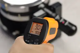 The temperature of the black plastic handle of the Bella 13991 is being measured using a thermometer. The screen reads 90.5°F.