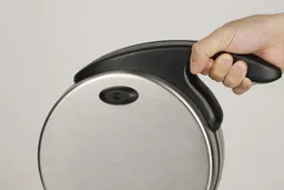 The Presto 03510 Ceramic Flipside Belgian waffle maker’s handle being held in one hand by a product tester.