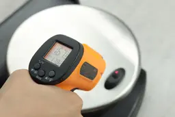 The temperature of a plastic foot of the Presto waffle maker is being measured using a thermometer. The screen reads 167.9°F.