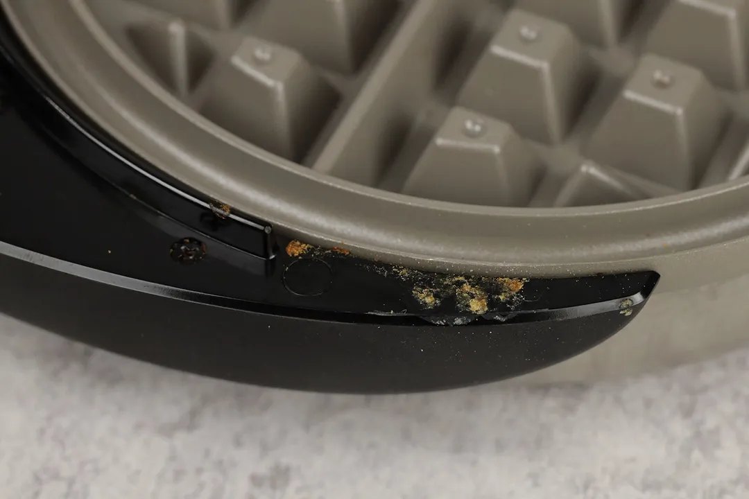 Close-up on the gunks accumulated on the inner part of the black plastic handle of the Presto Belgian waffle maker.