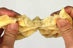 A waffle being torn down the middle by hand to test it for its consistency. The golden interior of the waffle is revealed.