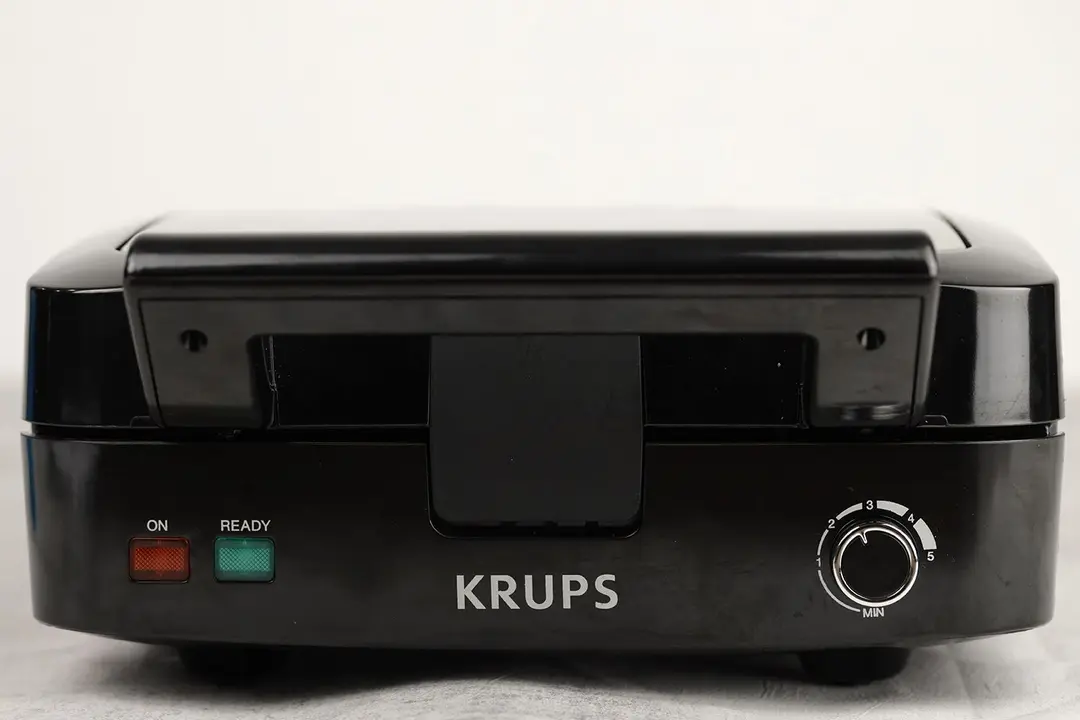 A close-up of the control panel of the KRUPS waffle maker. Two indicator lights and a browning control dial knob can be seen.