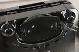 The grommet at the bottom of the KRUPS. It helps the user manage the power cord when the waffle maker is put in storage.