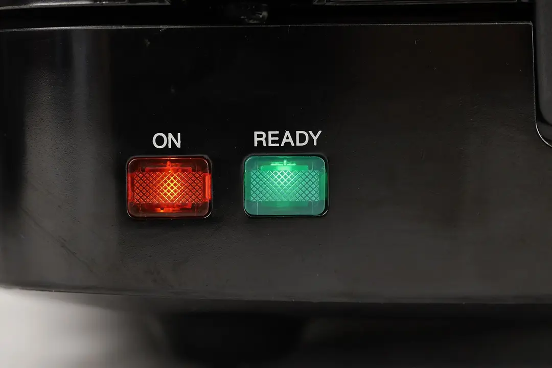 The two indicator lights of the KRUPS Belgian waffle maker: the left is the red ON light, and right is the green READY light.