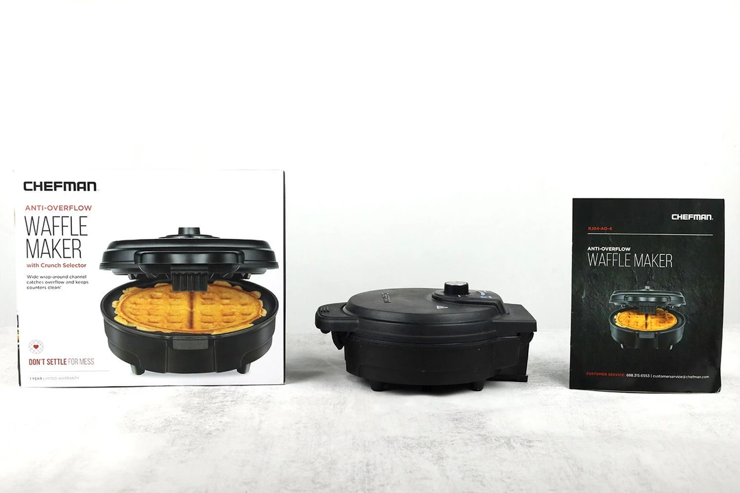 The black Chefman Anti Overflow Belgian waffle maker in center. Its manual is to the left and the shipping box to the right.
