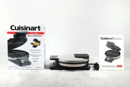 The Cuisinart WMR-CA Classic waffle maker on a table, with its instruction manual to the right and the shipping box it comes in to the left.