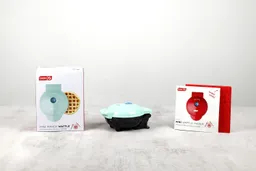 The aqua-colored Dash Mini waffle maker next to its shipping box (left) and instruction manuals (right).