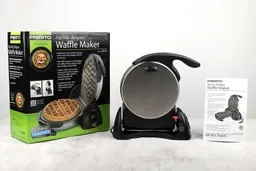 The Presto waffle maker on its side, to its right is the instruction manual and to its left is the shipping box.