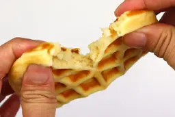 The waffle is torn down the middle by hand to test it for its consistency, revealing the spongy inner core.