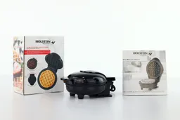 The Holstein personal waffle maker next to its shipping box (left) and instruction manual (right).