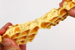 A waffle being torn down the middle by hand to test it for its consistency. The air bubble-filled core is revealed.