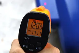 The temperature of the top side of the DASH No-Drip’s handle is being measured with a thermometer. The screen reads 120.0°F.