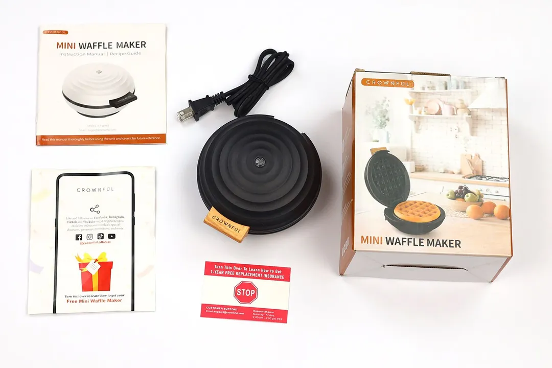 The Crownful 4 inch waffle maker in the middle, with its warranty card, instruction manuals, and shipping box around it.