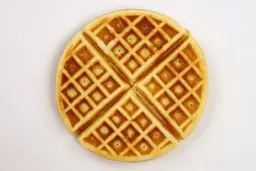 The dark brown - golden bottom crust of a waffle cooked for 5 minutes.