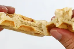 The waffle, which has been cooked for 7 minutes, is torn by hand in order to test for its consistency and texture, revealing the fluffy core inside.