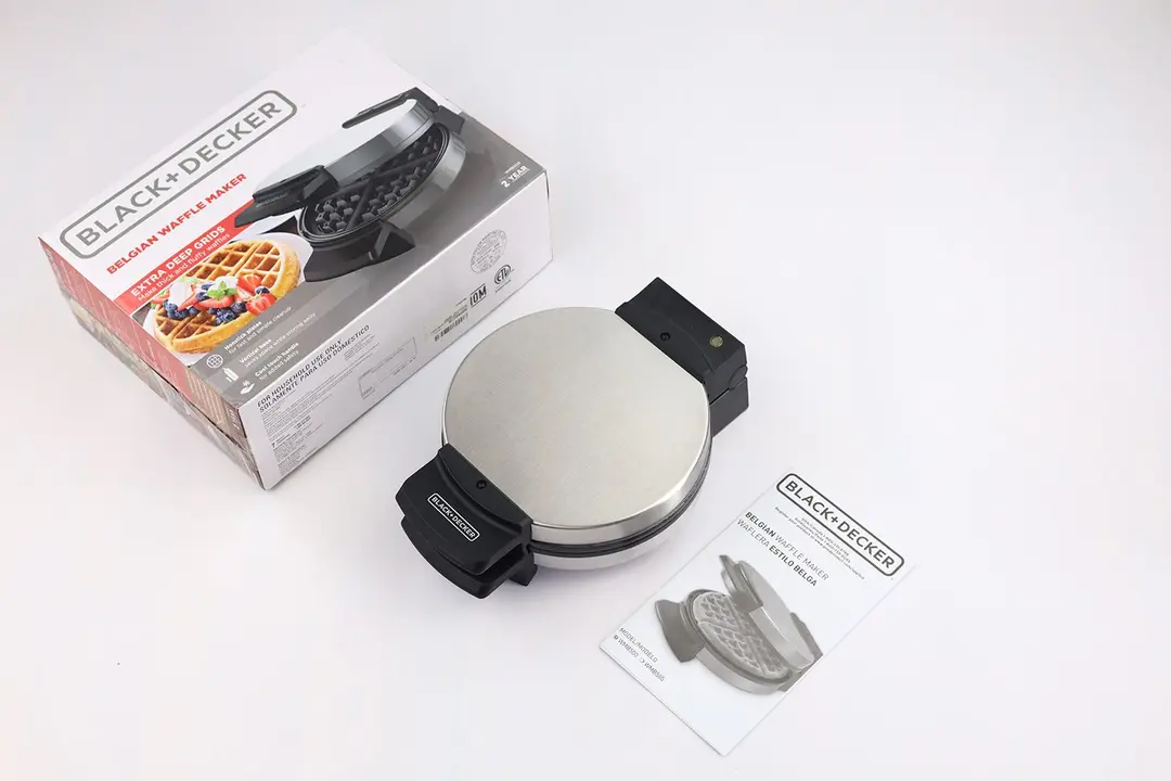 The black and silver Black and Decker waffle maker WMB500 next to its instructional manual and shipping box.