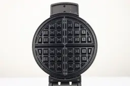 A close-up view of the glossy, black, Belgian-style waffle plate of the Black and Decker WMB500 waffle maker.
