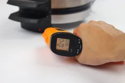 The surface temperature of the Black and Decker WMB500’s base is being measured using a thermometer in a thermal safety test. The screen reads 104.2°F.