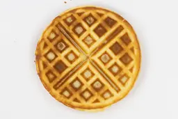 The very dark brown bottom crust of a waffle baked for 5 minutes using our self-mixed recipe.
