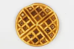 The very dark brown-dark gold top crust of a waffle baked for 5 minutes using our self-mixed recipe.