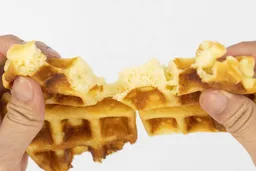 A waffle baked in 5 minutes being torn by hands to reveal the inner core during a texture test.