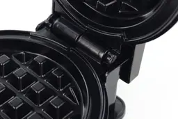 The black plastic hinges of the Holstein waffle maker’s lid. It is currently in its open position.