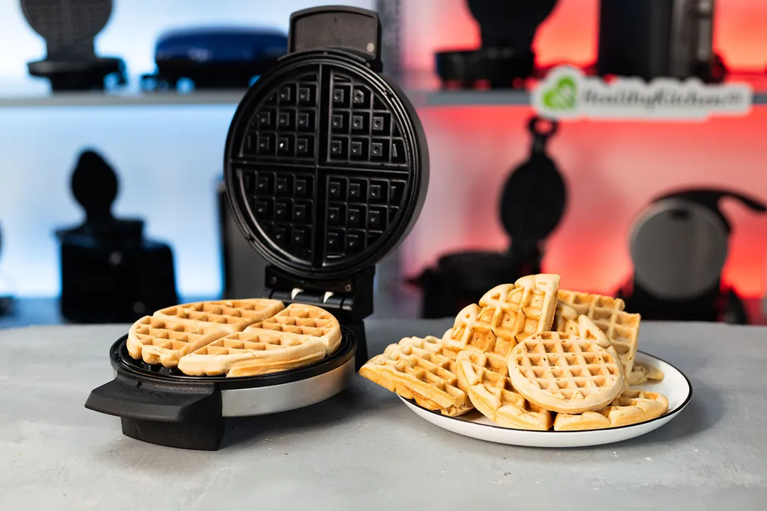 BLACK+DECKER WMB500 waffle maker next to a plate of waffles on a gray countertop.