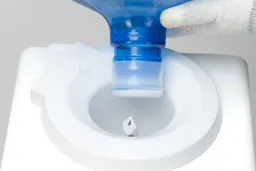 A water bottle being mounted onto the water needle of a top loading water cooler dispenser.
