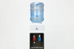 Bottle of water resting in place on a top loading water cooler dispenser.