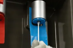 A close up showing how to clean inside the water nozzle of a water cooler dispenser using a cotton Q-tip.