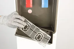 Close up of a hand holding a detached drip tray removed from its hold on a water cooler dispenser.