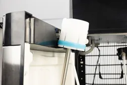 A bottle cap of a bottom loading water cooler dispenser changing on the cabinet door hook during a bottle change.