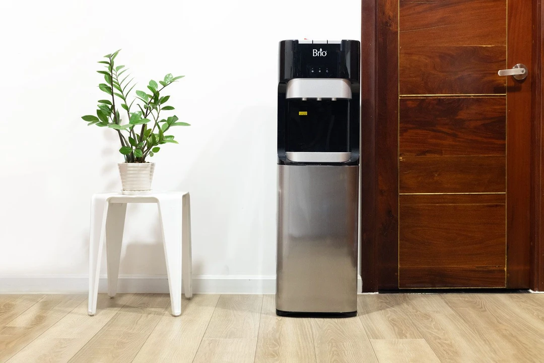 Brio Bottom Load Water Dispenser (CLBL420V2) pictured standing by a door with a potted plant to the left.