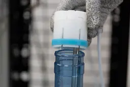 Close up of a plastic bottle cap being placed onto a bottom-loading water cooler dispenser.