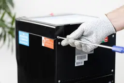 A gloved hand using a screwdriver to open the hood of a water cooler dispenser.